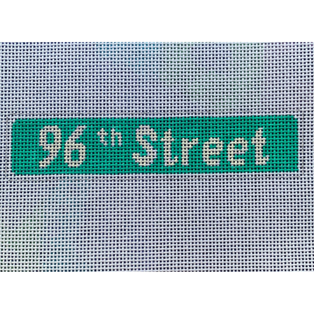 A needlepoint canvas with the text '96th Street' in green, indicating the kit's purpose for learning needlepointing techniques.